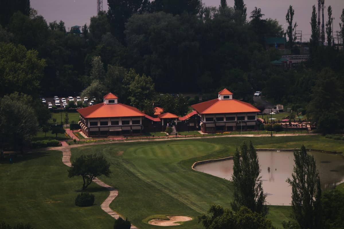 Golf course with clubhouse buildings and a pond beyond the fairway