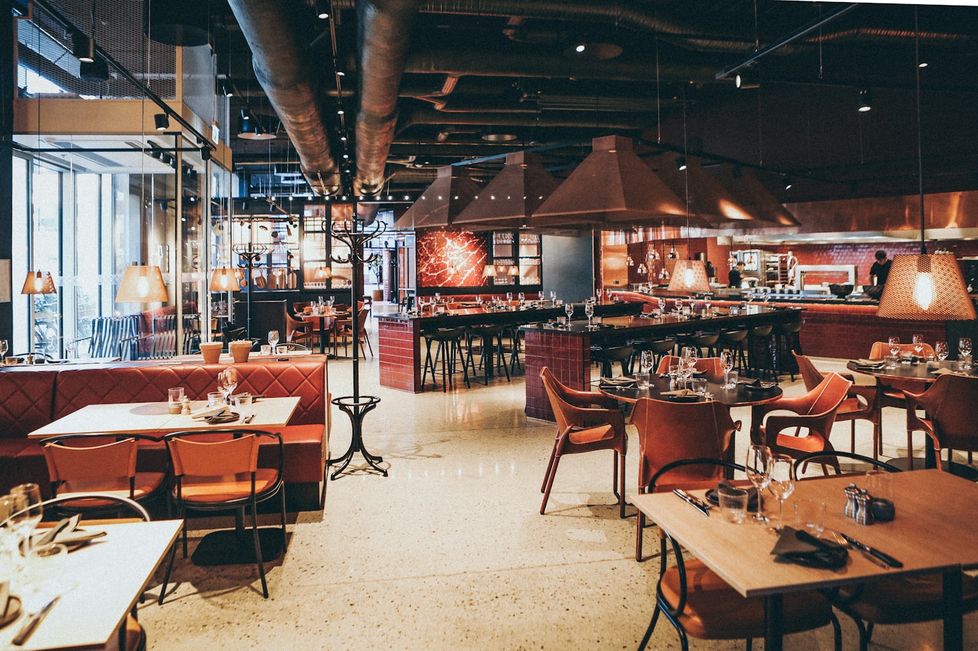 Dining room of a restaurant set for service, open kitchen behind the bar